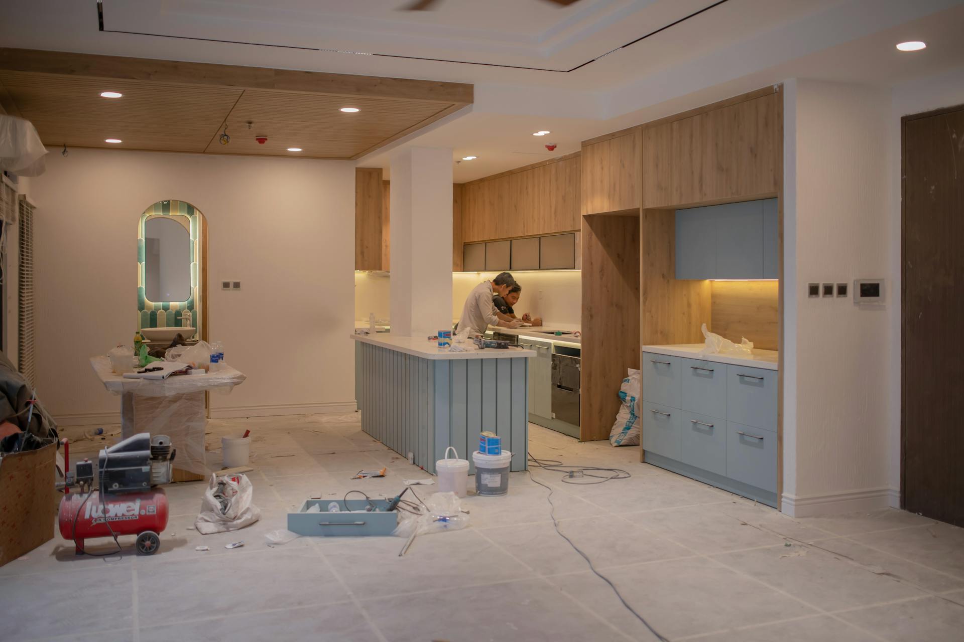 Kitchen remodel mid-construction with workers installing cabinets